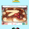 Dessert créatif façon tiramisu, présenté dans un plat rectangulaire en verre. Le dessus est saupoudré de cacao et décoré avec des fruits goyavier et deux biscuits cuillère croisés. Le plat repose sur une nappe fleurie. En arrière-plan, une bannière "La Réunion des cuisines" encadrée de cœurs rouges, avec une illustration tropicale mêlant palmier et drapeau italien en forme de cœur. Ambiance festive et métissée, célébrant la fusion culinaire entre La Réunion et l’Italie