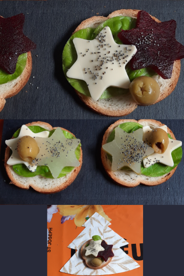 Trois bouchées festives présentées sur des tranches de pain, décorées de feuilles vertes, étoiles de fromage blanc et de betterave, olives vertes et graines de pavot. Chaque composition évoque une ambiance de fête, avec une touche créative et végétale. En bas, une bouchée repose sur une serviette en forme de sapin, renforçant l’esprit de Noël.