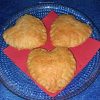 Trois cœurs feuilletés dorés posés sur une serviette rouge, présentés dans une assiette en verre, sur une nappe bleue.