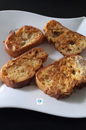 Gros plan sur quatre tranches de pain de boulanger enrobées d'œuf et de basilic, parfaitement dorées