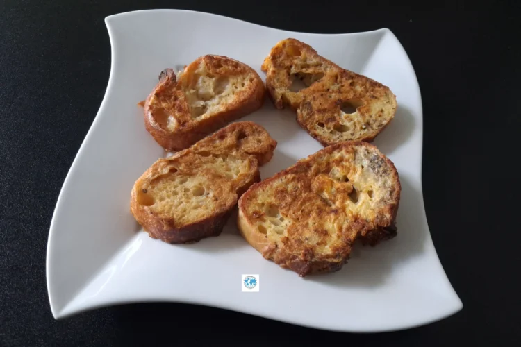 Gros plan sur quatre tranches de pain de boulanger enrobées d'œuf et de basilic, parfaitement dorées