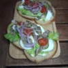 Délicieuses tartines créoles sur un plateau en bois, garnies de tomates cerises, oignons rouges, fromage de tête et œufs.