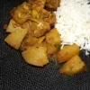 Une assiette noire texturée présentée avec un carry porc chouchou, plat traditionnel de La Réunion. En bas, à droite est visible le logo "La Réunion des cuisines"