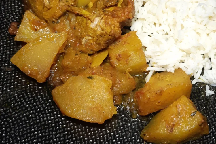 Une assiette noire texturée présentée avec un carry porc chouchou, plat traditionnel de La Réunion. En bas, à droite est visible le logo "La Réunion des cuisines"